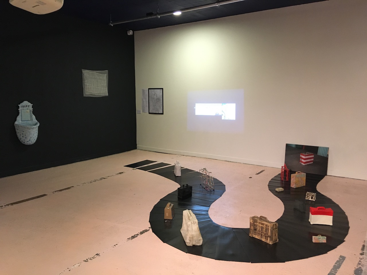Vue d'exposition, avec une installation de valise sur un tapis roulant en caoutchouc  en premier plan