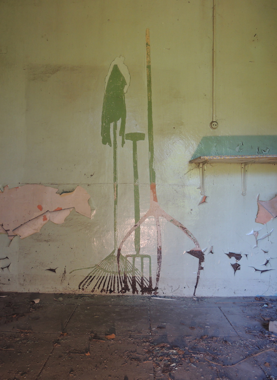 Dessin de rateau et fourches gratté dans les couches de peintures d'un mur vert amande