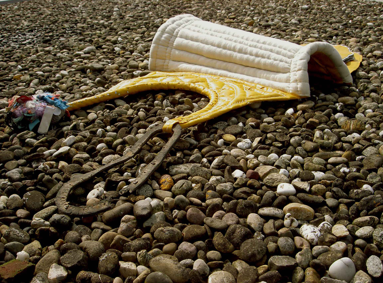 Sculpture au sol d'une selle de frontière en tissu, bâche de camion jaune, gris-gris amulettes et un pourtour de semelle de chaussure