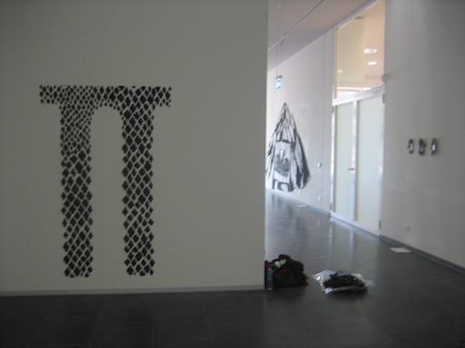 Installation au mur d'une accumulation de petits motifs en chambre à air cloués avec une montagne en textile peint à l'encre de Chine de Merina Beekman accrochée au mur au fond