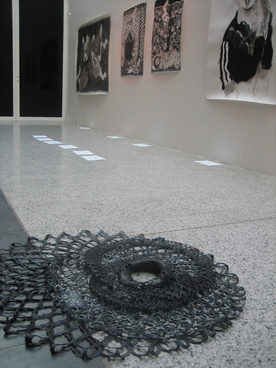 Installation au sol de chambres à air dentellées avec des dessins à l'encre de Chine de Merina Beekman accrochés au mur au fond