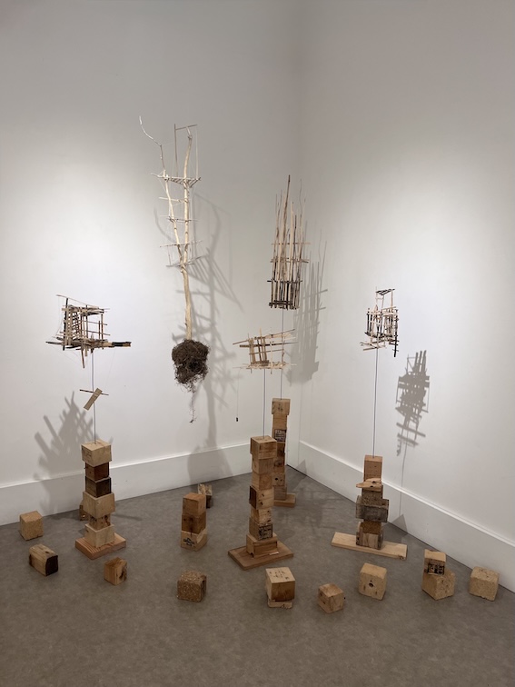 Installation de sculpture en bois de cagette, cabanes sur socle et dans un citronnier suspendu