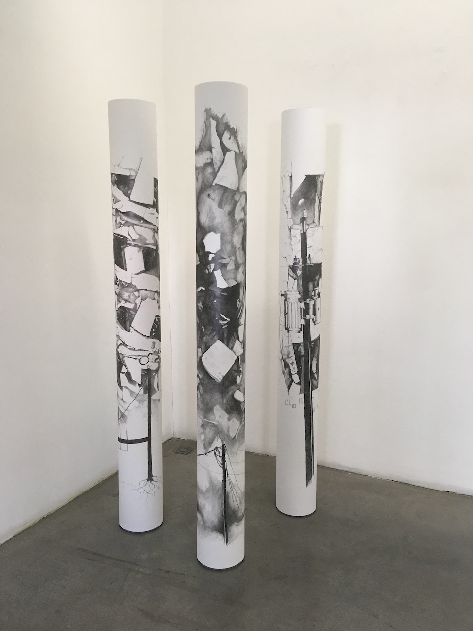 Série de 3 dessins au graphite d'architectures explosées qui présentent une forme d'arbre. Les dessins sont présentés sous forme de rouleaux de papier posés debout.