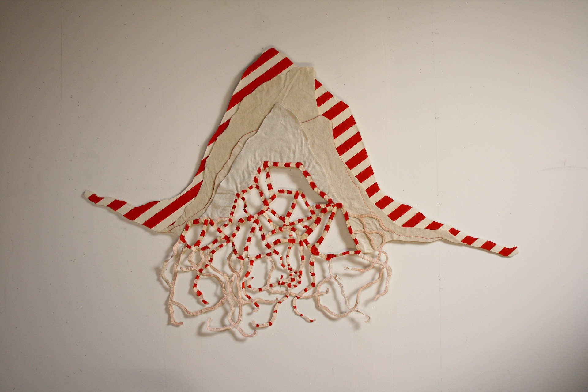Objet mural qui évoque un gonflement de la ligne de la frontière dans lequel vient s'installer un village de tentes, en tissu, strié de rouge et blanc.