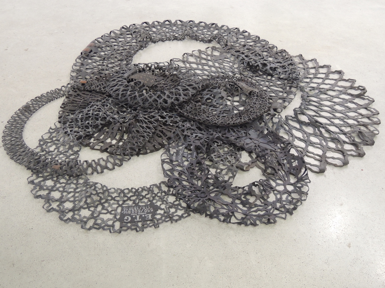 Installation au sol de chambres a air de camions, tracteurs, voitures, vélos, ajourées en dentelle au ciseaux avec des motifs orientaux